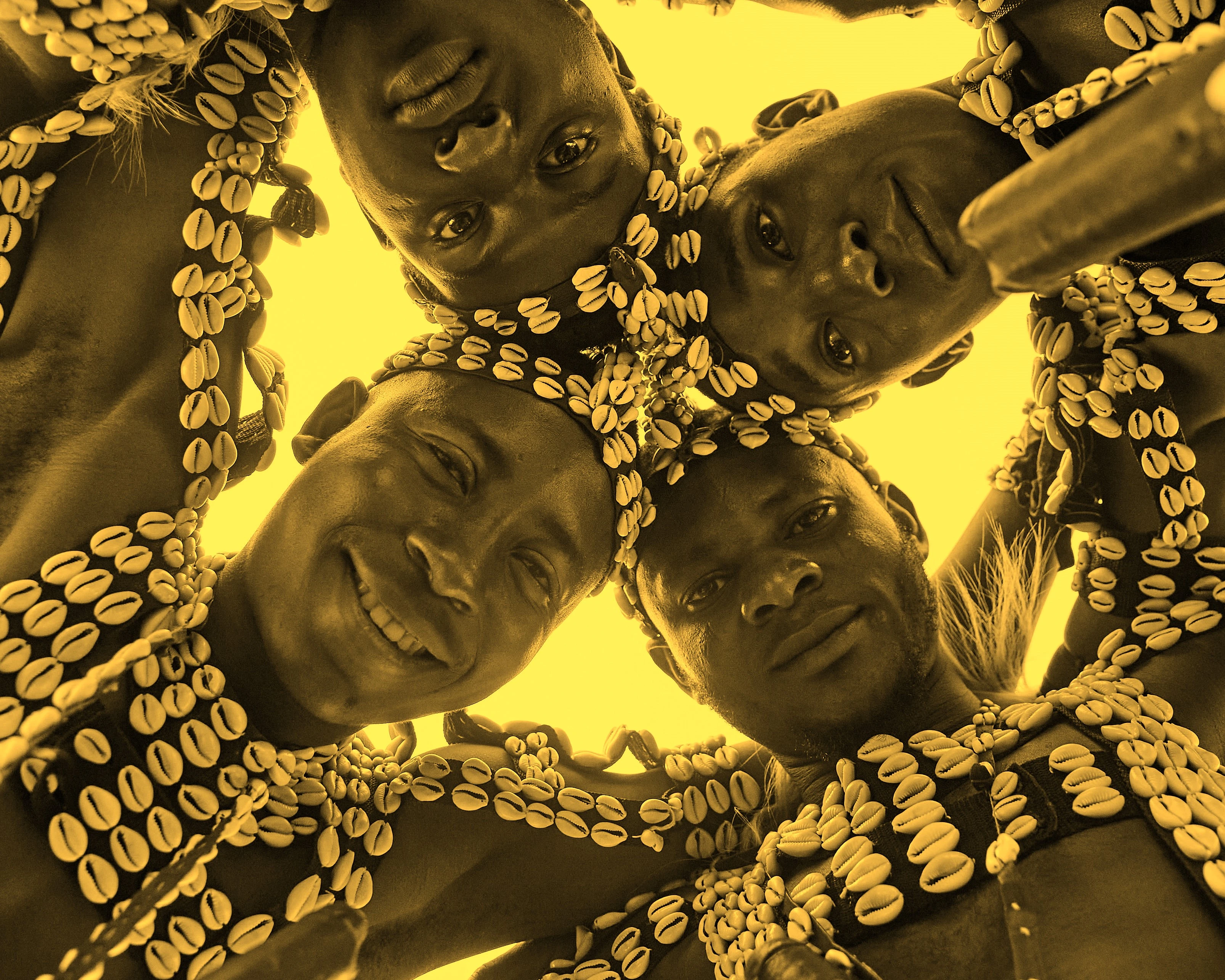 A group of men wearing cowrie shells embracing each other in togetherness 
