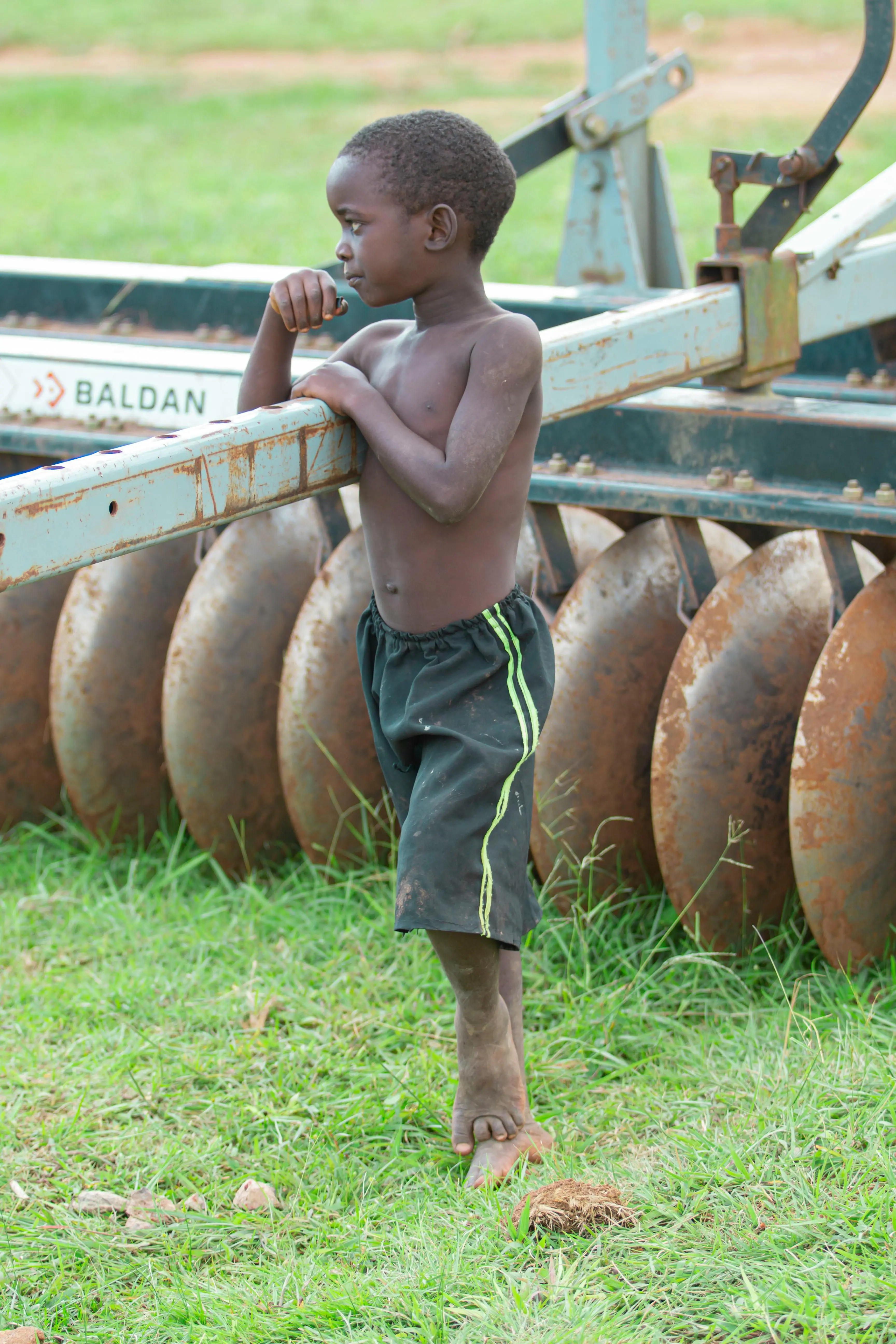 A photo of a shirtless boy leaning onto a tractor