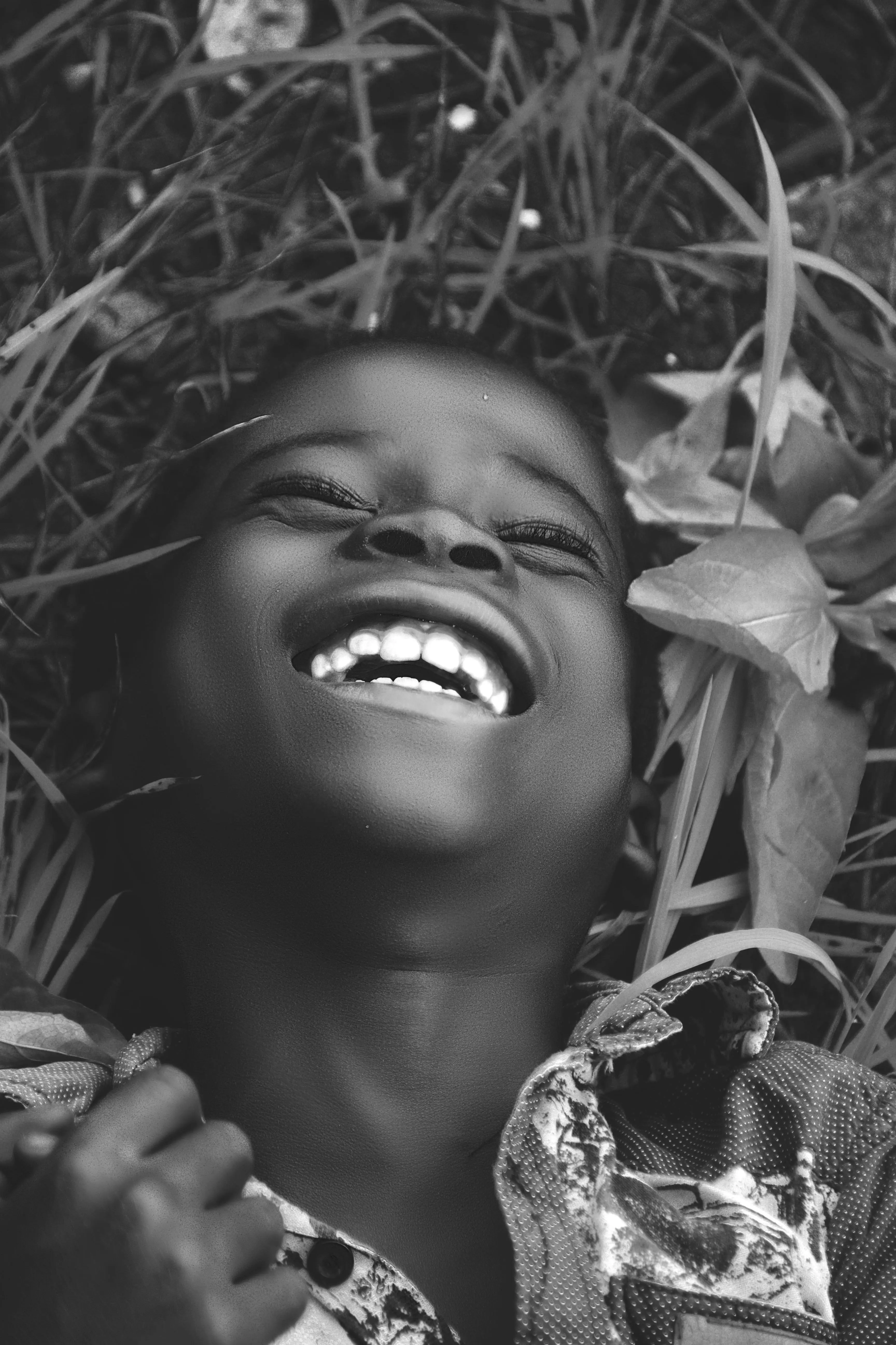 A happy boy laying on grass as he laughs