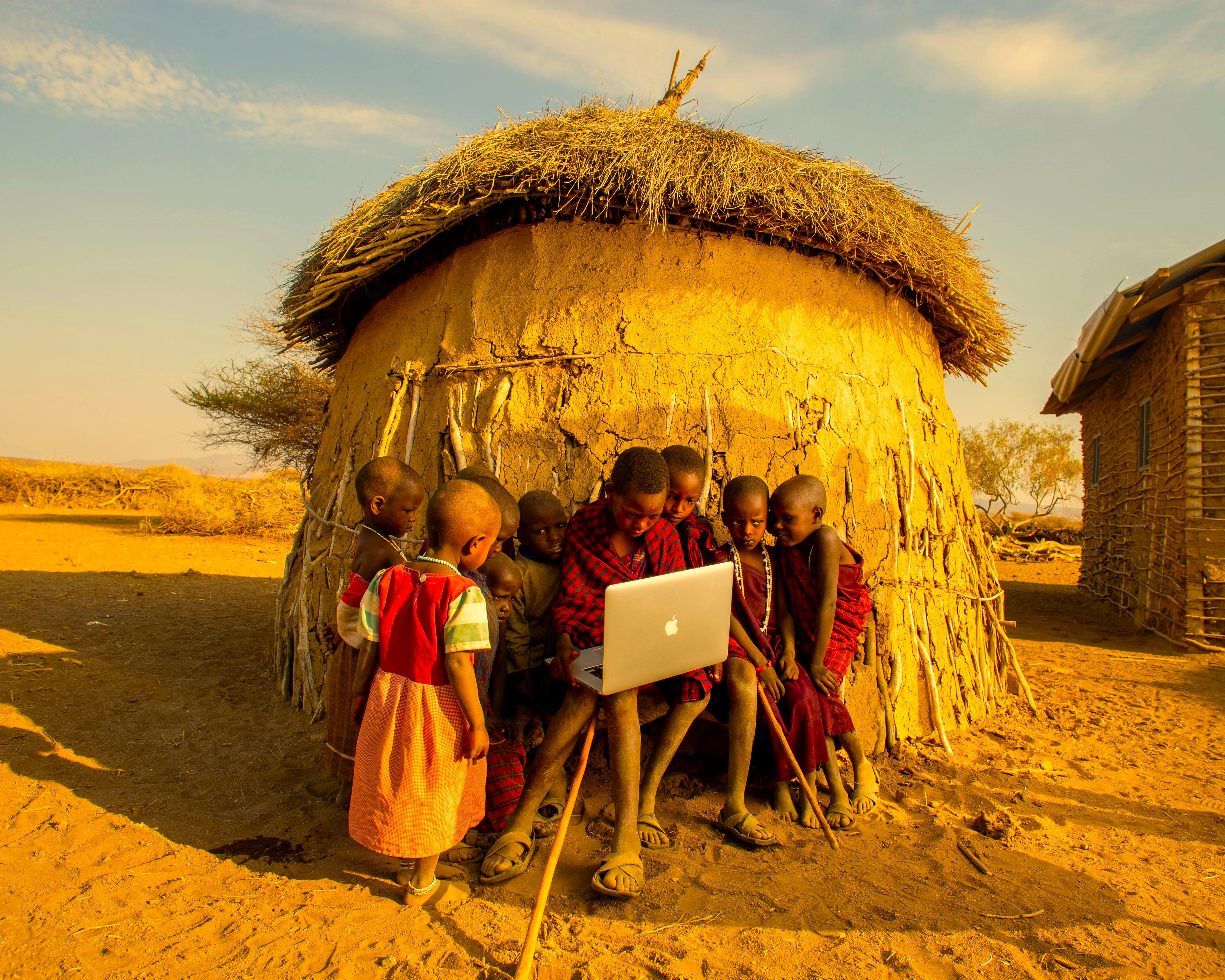  A photo of maasai children holding a macbook laptop